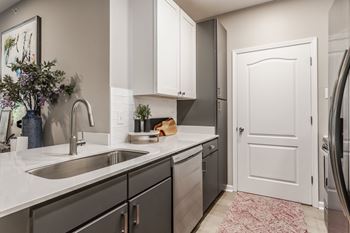 A kitchen with a sink and a door to a refrigerator